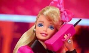Foto Barbie anni 80 con un fiocco rosa in testa e il telefono di quegli anni