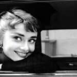 Audrey Hepburn poggiata al finestrino dell'auto che sorride