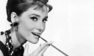 Iconica foto di Audrey Hepburn in colazione da Tiffany, con il volto a tre quarti e la sigaretta tra i denti