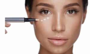 make up artist applica piccole dosi di correttore sul viso di una ragazza