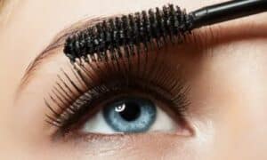 primo piano di un occhio chiaro a cui si sta applicando del mascara