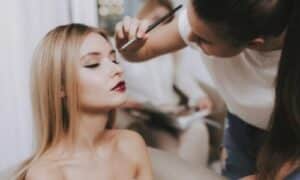 make up artist applica il trucco cateyes su una donna con le labbra già tinte di rosso