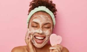 Ragazza, con il sapone detergente su volto, tiene in mano un cuore rosa per sottolineare quanto sia importante prendersi cura della pelle del viso