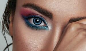 occhio in primo piano con un make up colorato, tra ombretto rosa e eyeliner a doppia coda celeste che si unisce all'angolo esterno dell'occhio
