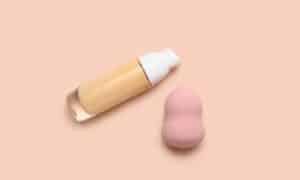 raffigurazione di un fondotinta e una beauty blender su uno sfondo nude