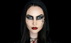 Viso in primo piano di una modella con carnaggione pallida e trucco gotico total black con rossetto rosso e nero ai bordi