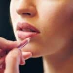 Makeup artist crea uno trucco anni 60 rifinendo i contorni delle labbra con una matita nude