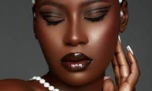 In primo piano il volto di una donna con un trucco occhi formato principalmente da una fantasiosa forma di eyeliner, non solo la riga sopra la rima delle ciglia superiori continua fino alla piega della palpebra mobile, ma sopra di essa, più piccola c'è una doppia ala