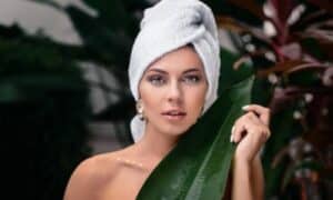 Modella con asciugamano sulla testa e una foglia a coprirle il corpo, mostra il make up occhi per le iridi Hazel