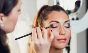 Truccatrice professionista usa un pennello per sfumature per creare la punta scura dello smokey eyes