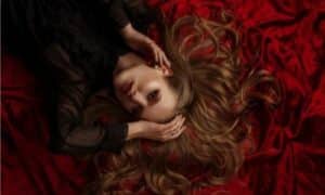 immagine di una ragazza sdraoiata su del velluto marsala che mostra un make up molto intenso sempre marsala