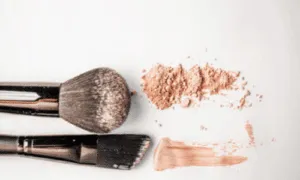 due pennelli da fondotinta con polvere e crema accanto