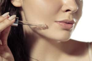 primo piano di una ragazza che appica primer trucco viso estivo