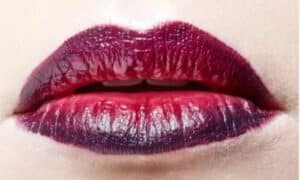 foto in primo piano di labbra con rossetto marsala
