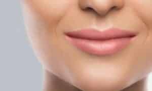 Foto in primo piano di una bocca sorridente con rossetto nude rosato