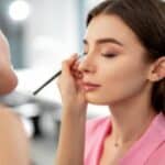 Truccatrice passa un ombretto del colore giusto per l'armocromia della modella