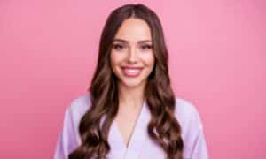 Donna con lunghi capelli castani truccata di roa come la Barbie