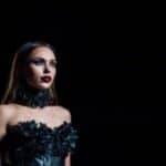 Modella vestita in stile gotico con un vestito a rose nero, rossetto rosso con sfumature nere ai bordi e makeup occhi con smokey goth