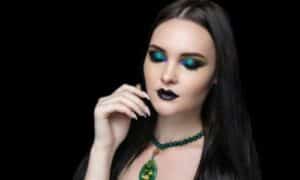 Modella truccata con un look gotico con rossetto nero e il makeup occhi nero e verde