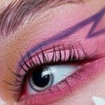 Occhio in primo piano di un trucco neon rosa con la linea dell'eyeliner viola disegnata sulla palpebra superiore