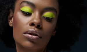 In primo piano il volto di una modella con un trucco neon su tutta la palpebra senza sfumature