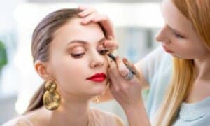 Makeup artist crea un make up per far sembrare gli occhi della modella più grandi, usando sfumature nude