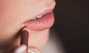 make up artist trucca le labbra di una donna con una matita neutra